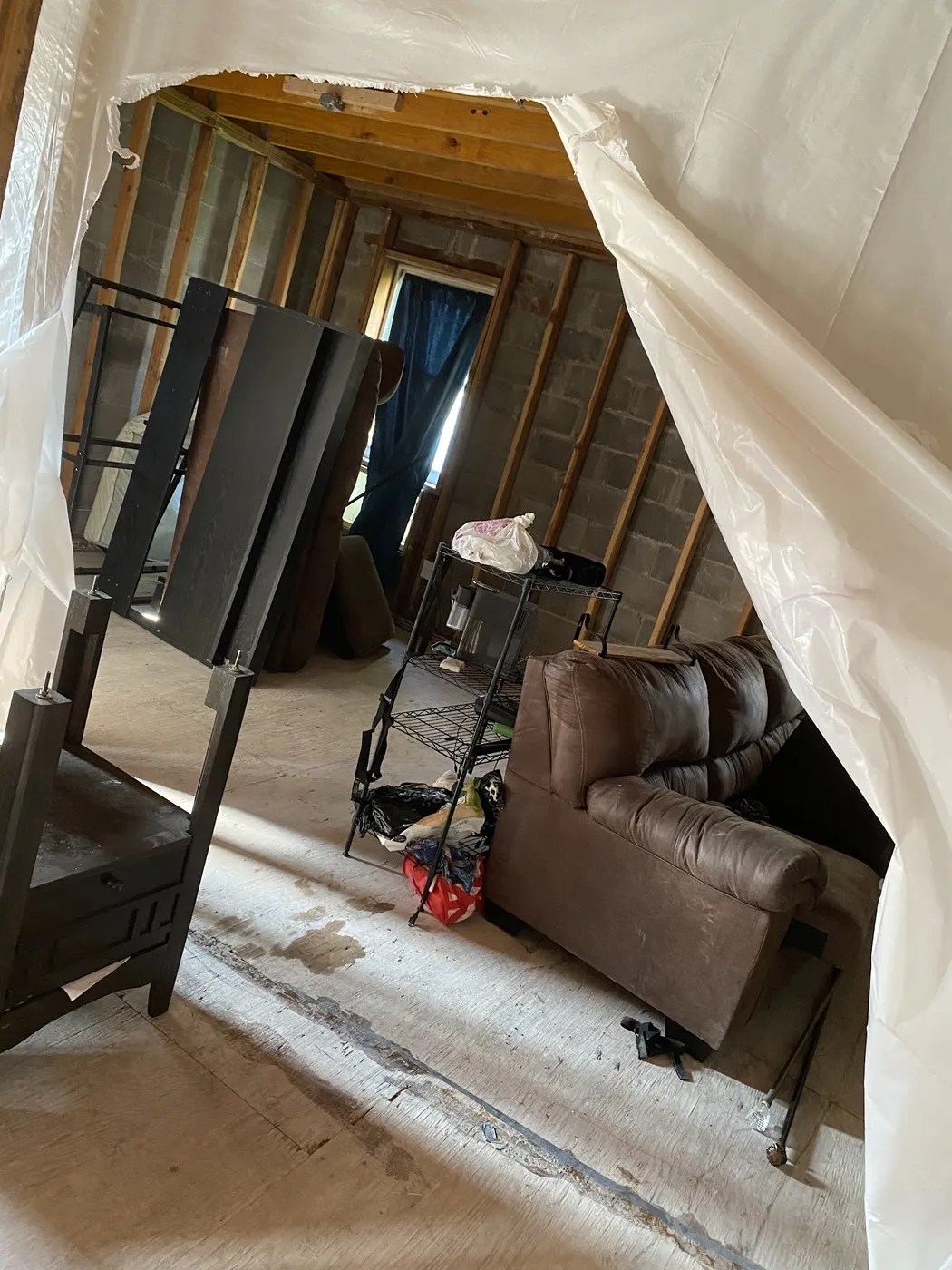 A doorway sealed with plastic sheeting during a move, with furniture waiting inside